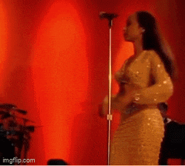 a woman is singing into a microphone on stage .