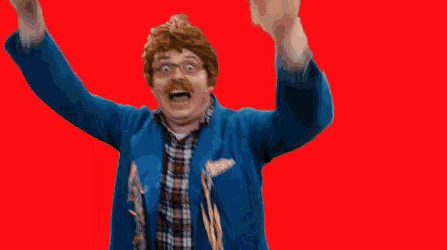 a man in a blue jacket and plaid shirt is making a funny face with his hands in the air