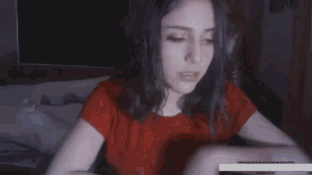a girl in a red shirt is sitting in a dark room .