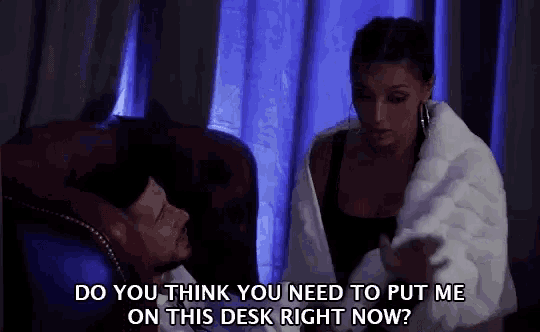 a man and a woman are sitting on a couch and the woman is asking the man to put her on the desk right now