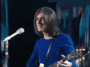 a man singing into a microphone while playing a guitar