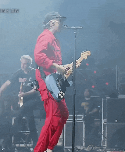 a man singing into a microphone while playing a guitar with the words time low visible in the background