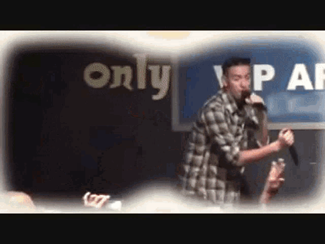 a man sings into a microphone in front of a sign that says only vip af
