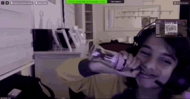 a girl wearing headphones is drinking water from a bottle