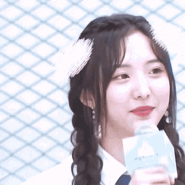 a young woman with braids is holding a microphone and smiling .