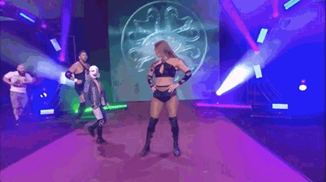 a woman in a mask is standing next to a wrestler on a red carpet .