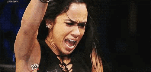 a woman is screaming with her mouth open while holding her arm up in the air .