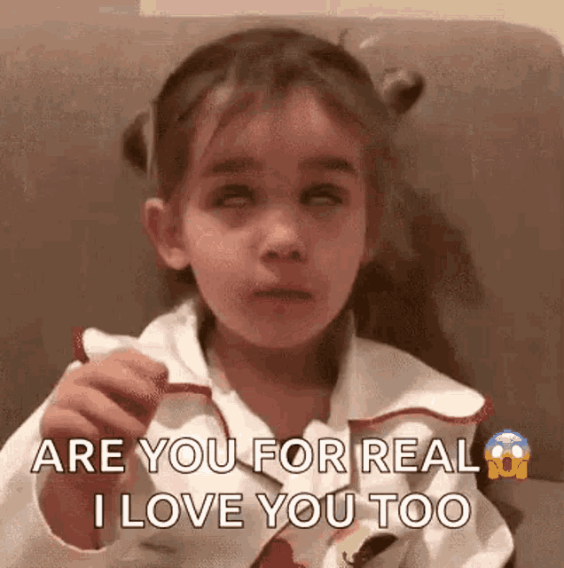 a little girl is crying and saying `` are you for real i love you too '' while sitting on a couch .