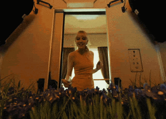 a woman in a yellow dress stands in front of a window