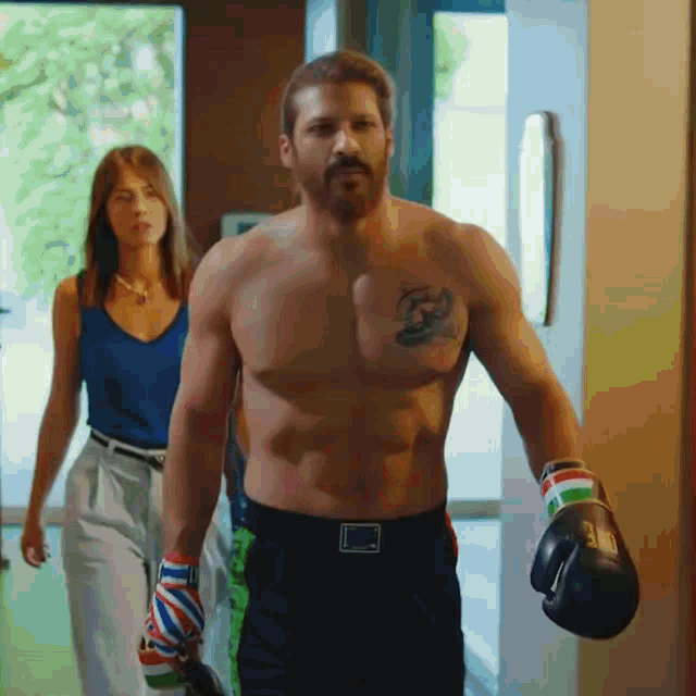 a shirtless man wearing boxing gloves and a tattoo on his chest