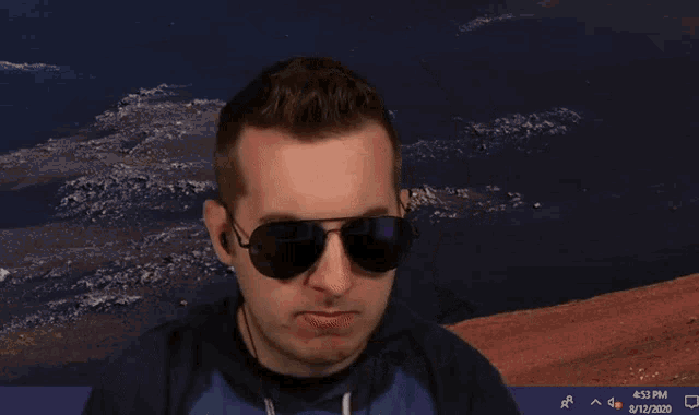 a man wearing sunglasses stands in front of a computer screen that says 4:53 pm