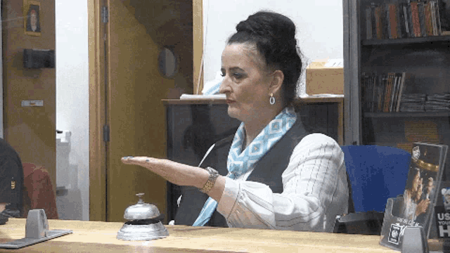 a woman sitting at a desk with a bell in front of her and a sign that says us your home