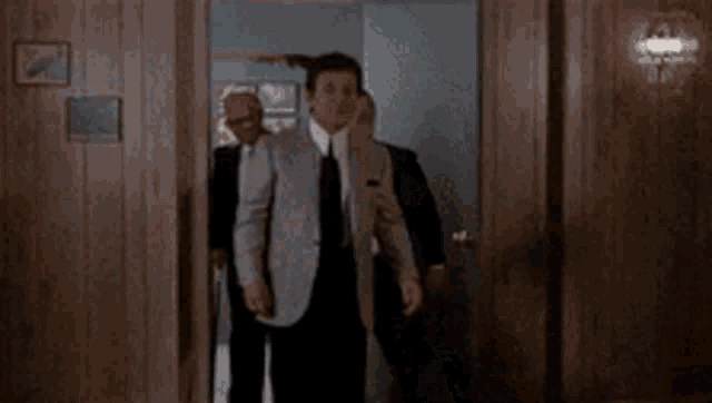 a man in a suit is holding a gun to his ear .