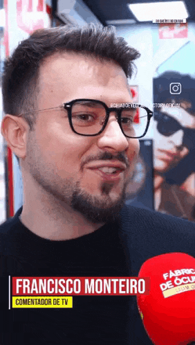 a man with glasses and a beard is talking into a microphone with the name francisco monteiro