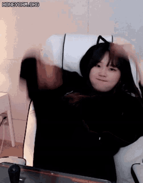 a girl is sitting in a chair with her hands in the air