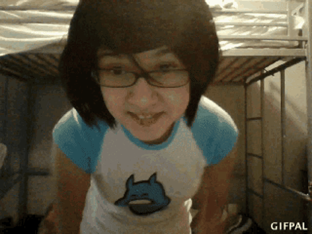 a girl wearing glasses and a blue shirt with a cat on it