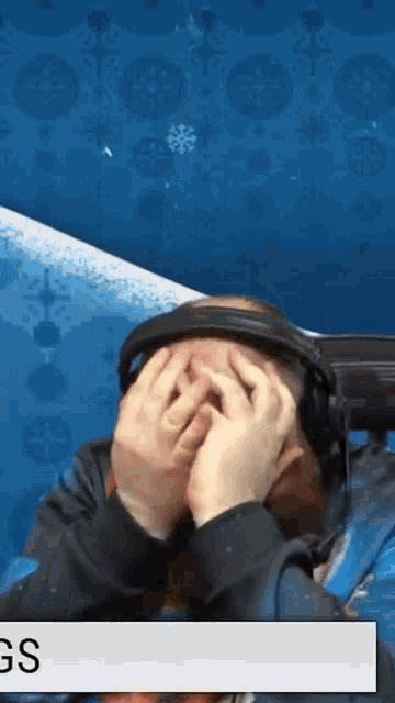 a person wearing headphones covering their face with their hands in front of a blue background that says gs