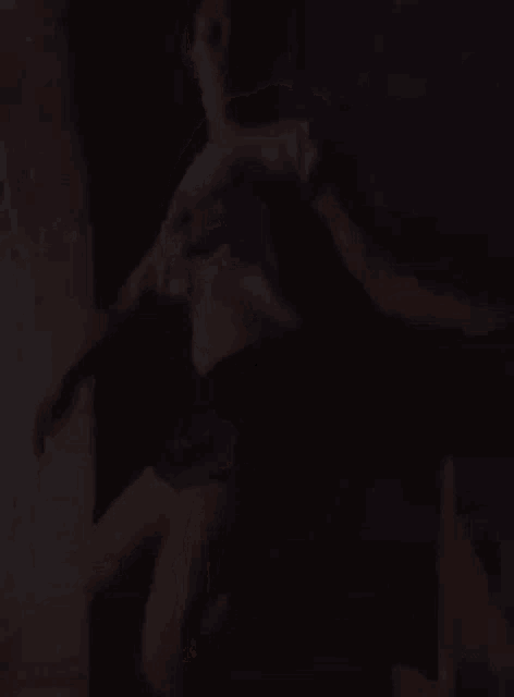a woman is dancing in a dark room with a blurred background .