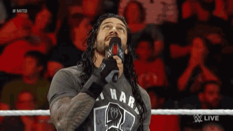 a wrestler is speaking into a microphone while wearing a shirt that says i war