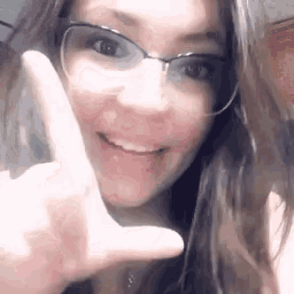 a woman wearing glasses is making a peace sign .
