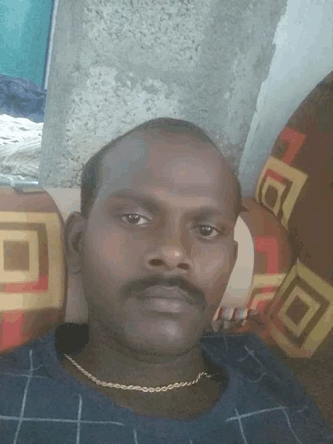 a man with a gold chain around his neck is laying on a colorful couch