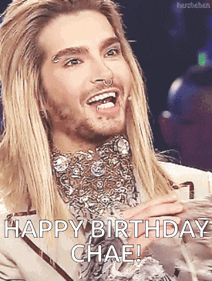 a man with long blonde hair and a beard is smiling and says " happy birthday chae "