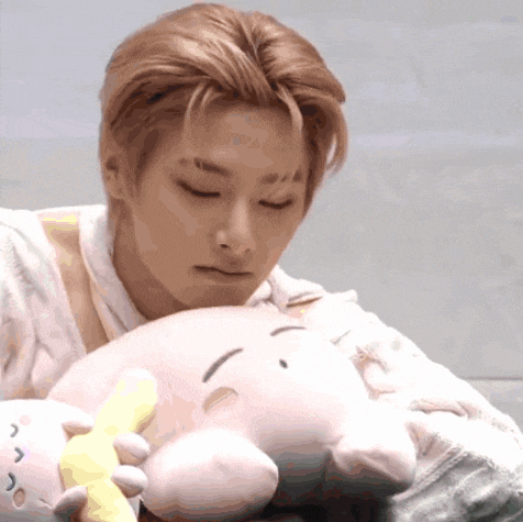a young man is holding a stuffed animal and looking at it with his eyes closed .
