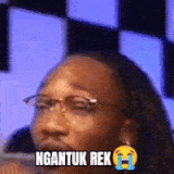 a man with glasses and a crying face is wearing a sticker that says ngantun rek .