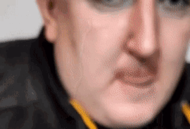a close up of a man 's face with a yellow collar making a funny face .