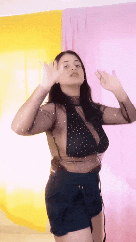 a woman wearing a black top and blue shorts is dancing