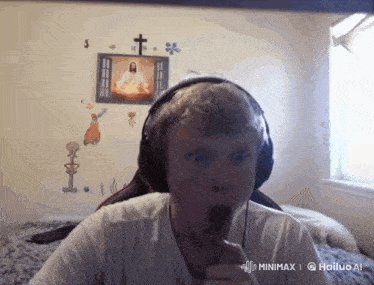 a man wearing headphones in front of a picture of jesus on the wall