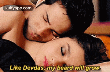 a man and a woman are laying on a bed and the woman is saying `` like devdas , my beard will grow '' .