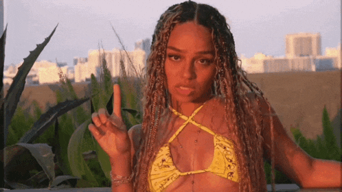 a woman in a yellow bikini is giving a middle finger
