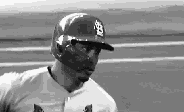 a black and white photo of a baseball player wearing a helmet and mask .