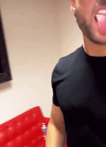 a man in a black shirt is standing in front of a red couch .