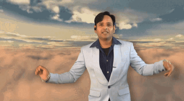 a man in a suit stands in front of a cloudy sky with his arms outstretched