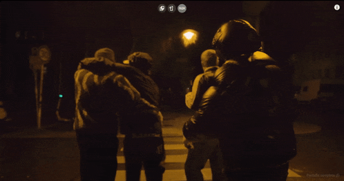 a man in a black jacket is standing in front of a fence at night