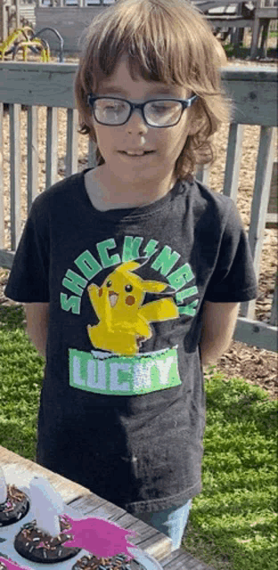a young boy wearing glasses and a shockingly lucky t-shirt