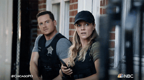 a man and a woman are standing in front of a brick building with nbc written on the bottom