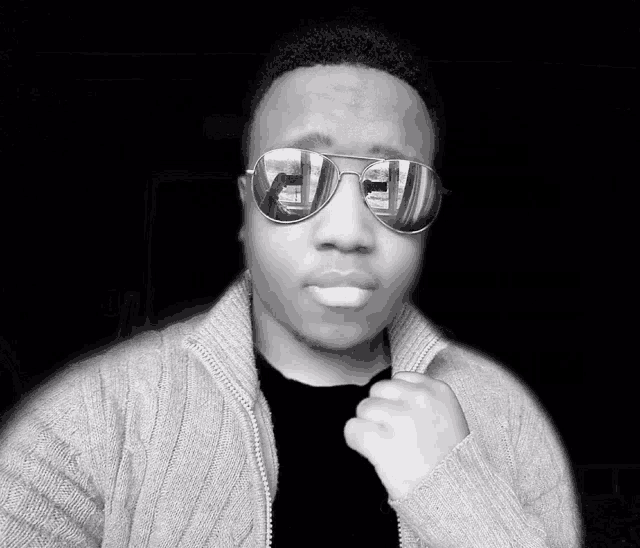 a black and white photo of a man wearing sunglasses with a reflection of a car