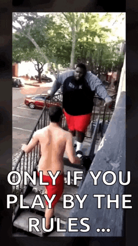 a man without a shirt is standing on a set of stairs next to a large man .