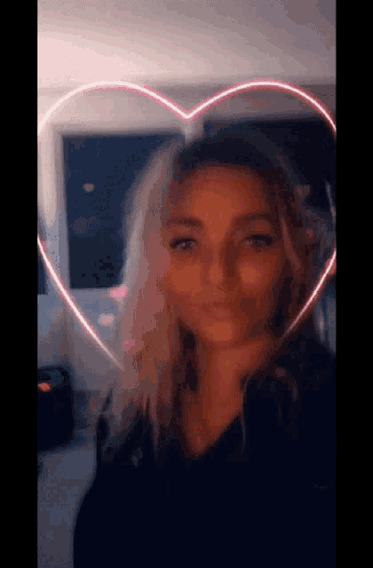 a woman is standing in front of a heart shaped light behind her