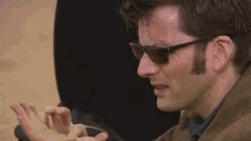 a man wearing sunglasses is eating something while sitting down .