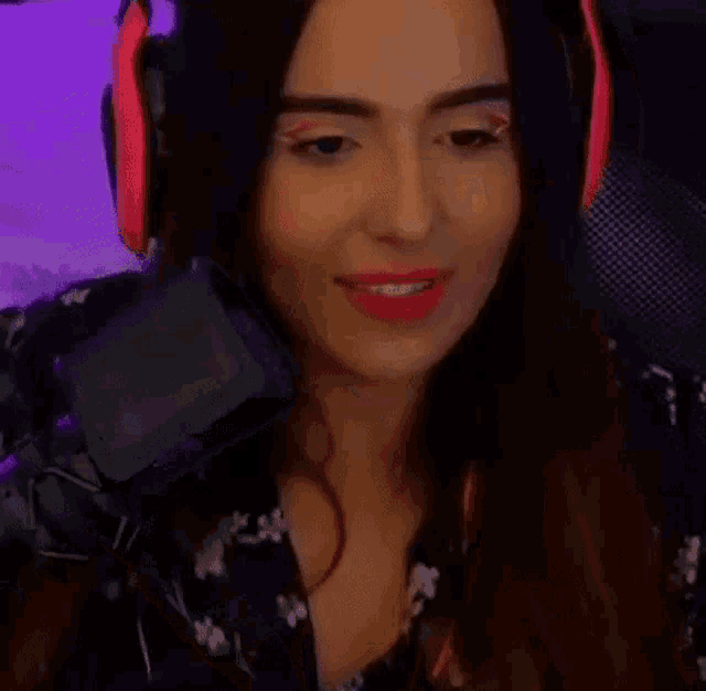 a woman wearing headphones and red eye shadow is playing a video game .
