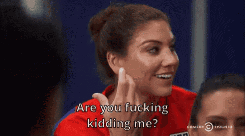 a woman in a red shirt is smiling and saying are you fucking kidding me ?
