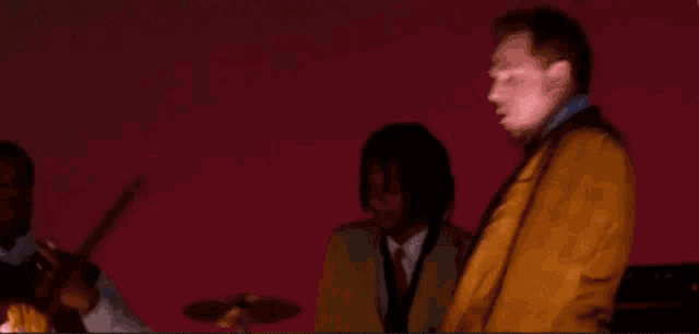 a man in a brown suit is playing drums in front of a blue sky