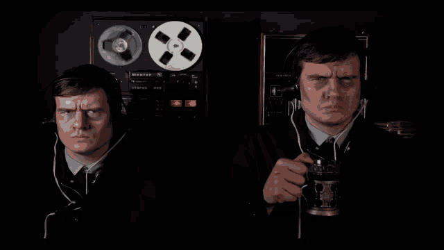two men wearing headphones are standing next to each other in front of a stereo