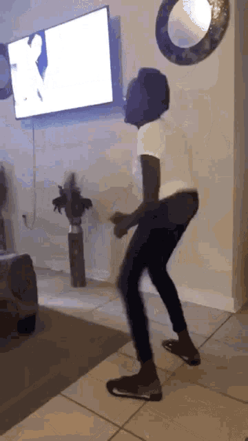 a person is dancing in a living room in front of a tv .