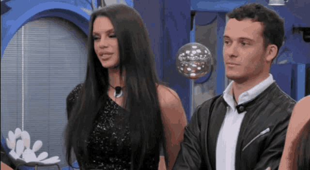 a woman in a black dress and a man in a black jacket stand next to each other