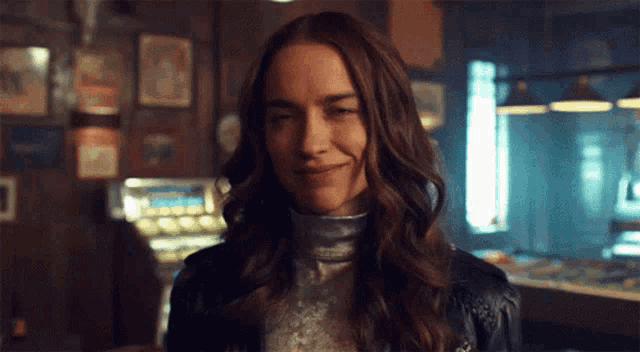 a woman is smiling in a dark room with a slot machine in the background